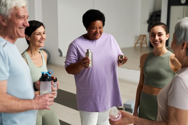 Groep volwassen mensen praten met instructeur na training in gezondheidsclub