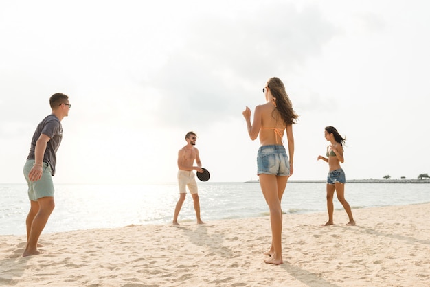 Groep vrienden die bij het strand in de zomer spelen
