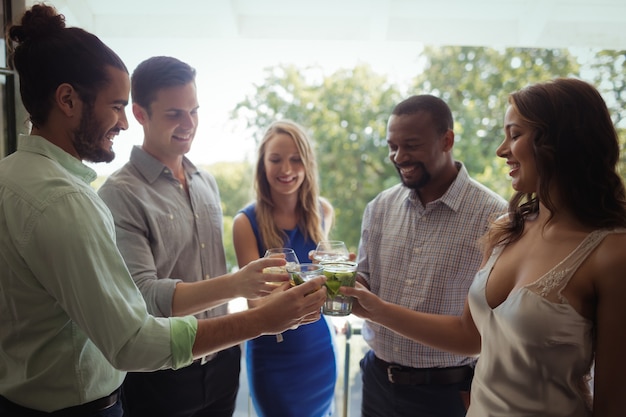 Groep vrienden die cocktailglazen roosteren