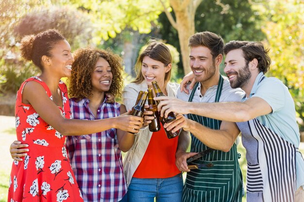 Groep vrienden die een bierfles in park roosteren