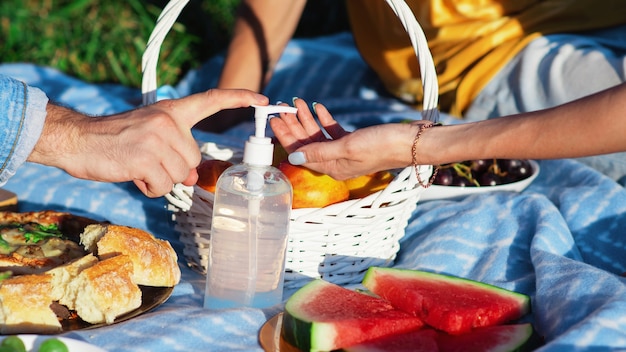 Groep vrienden die handen desinfecteren bij een picknick met lekkers