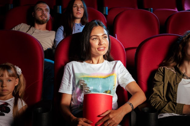 Groep vrienden die in bioscoop met popcorn en dranken zitten