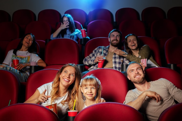 Groep vrienden die in bioscoop met popcorn en dranken zitten