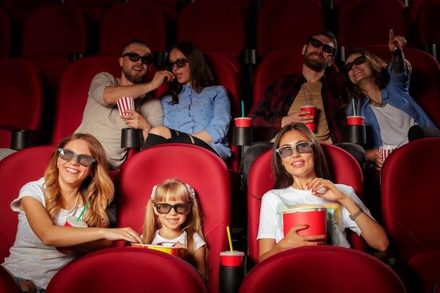 Groep vrienden die in bioscoop zitten met popcorn en dranken