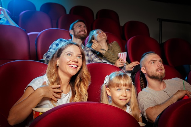 Groep vrienden die in bioscoop zitten met popcorn en drankjes