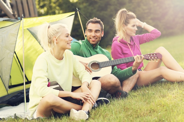 Groep vrienden die in het bos kamperen en gitaar spelen