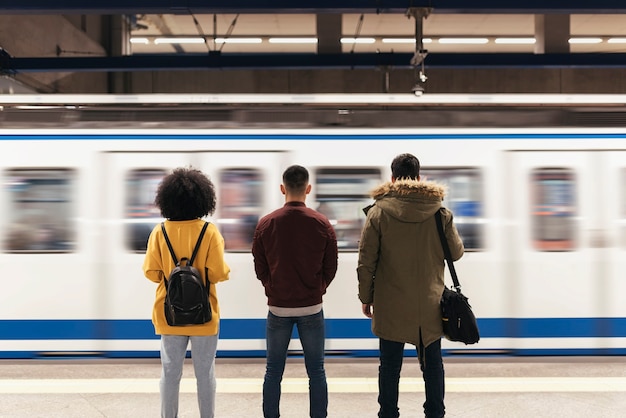 Groep vrienden die op de trein wachten op het perron van het metrostation. Openbaar vervoerconcept.