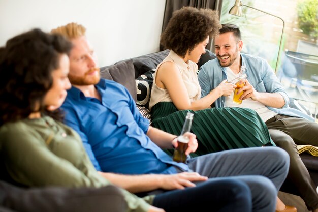 Groep vrienden die op tv letten, cider drinken en plezier hebben