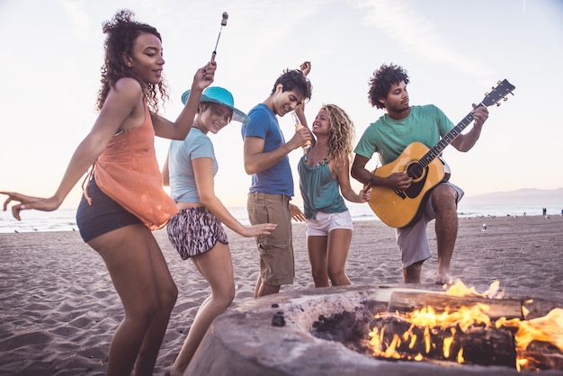 Groep vrienden die pret op het strand hebben die een bonefire maken