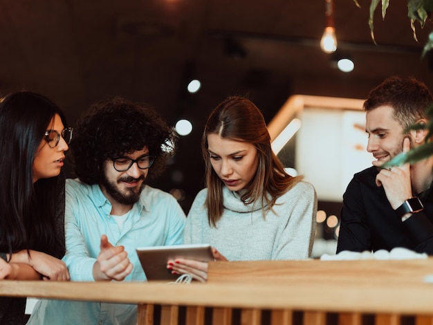 Groep vrienden die rondhangen in een coffeeshop met een laptop eronder. Gelukkige jonge mensen zitten in restaurants met behulp van een laptop