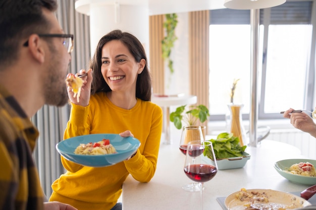 Groep vrienden die samen deegwaren in de keuken eten