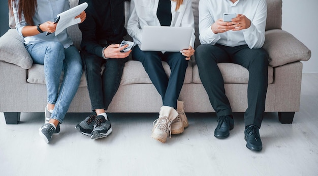 Groep vrienden die samen op de bank zitten met laptop en telefoons