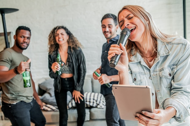 Groep vrienden die samen plezier hebben terwijl ze thuis karaoke spelen. Vrienden concept.