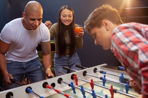 Groep vrienden die tafelvoetbal spelen bij bierbar