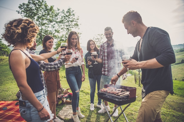 Groep vrienden die tijd doorbrengen met het maken van een picknick en een barbecue