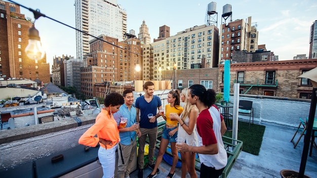 Groep vrienden die tijd samen doorbrengen op een dak in de stad van New York, levensstijlconcept met gelukkige mensen