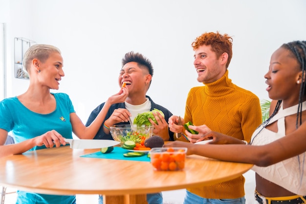 Foto groep vrienden die vegetarisch eten bereiden de salade bereiden en plezier hebben in de keuken