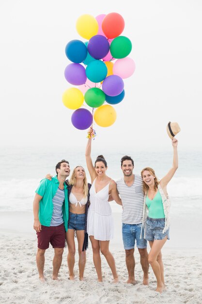 Foto groep vrienden die zich op het strand met ballons bevinden