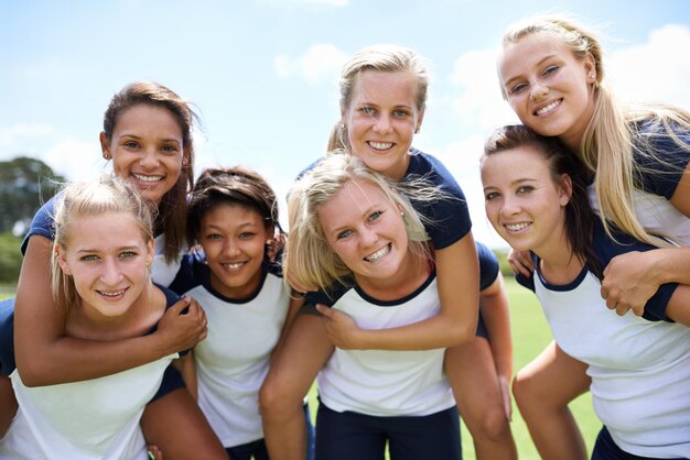 Foto groep vrienden en glimlachen op het veld met piggyback voor fitness sport en oefening met samenwerking teamwerk eenheid of vrouwen en portret gelukkig of blauwe hemel buiten in de natuur voor workout of training