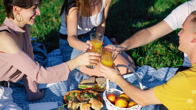 Groep vrienden gerinkelglazen met sap bij een picknick