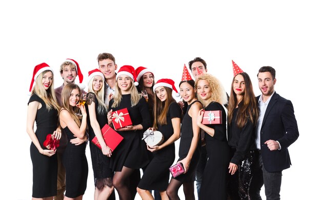 Groep vrienden in zwarte klassieke kleding met geschenken en kerstmutsen