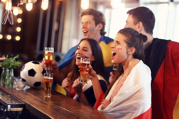 Groep vrienden kijken naar voetbalwedstrijd in pub