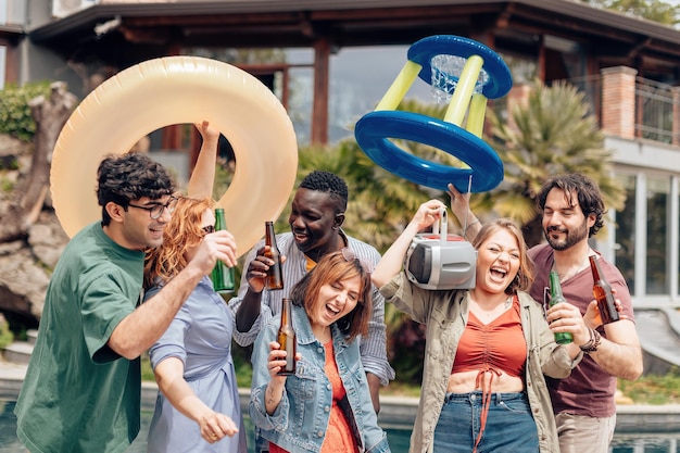 Groep vrienden lachen dansen met plezier aan het zwembad op een zomerse dag