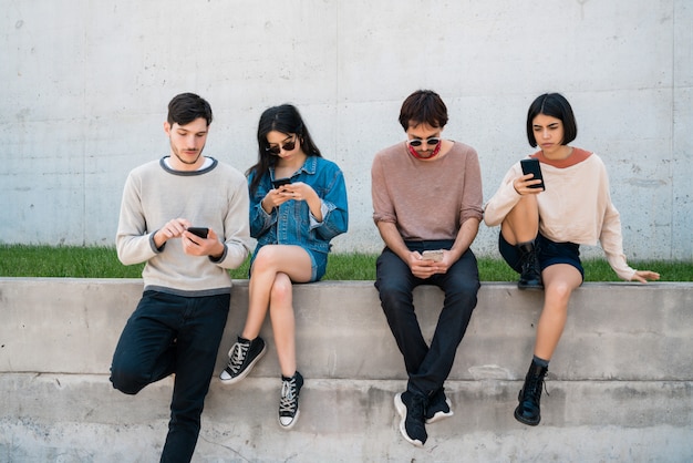 Groep vrienden met behulp van hun telefoons.