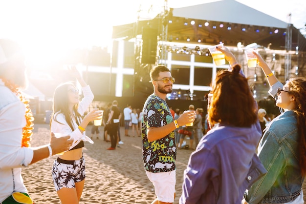 Groep vrienden met bier dansen en plezier maken op muziekfestival samen summer beach party