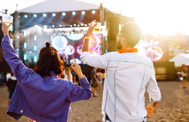 Groep vrienden met bier dansen en plezier maken op muziekfestival samen Summer Beach party