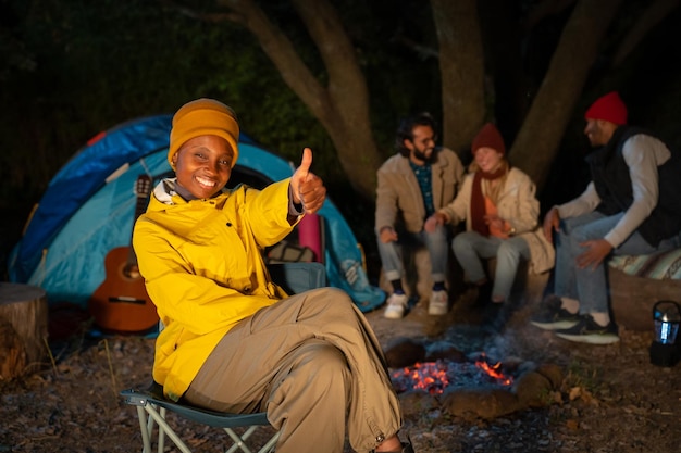 Groep vrienden met gitaar bij het vuur en kamperen buiten in het reisconcept van de middag