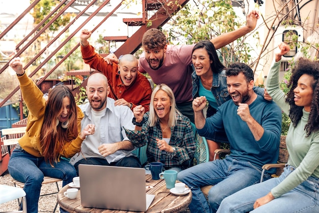 Groep vrienden op de universiteit kijken naar wedstrijd op laptop jonge reizigers die samen sport vieren in de jeugdherberg