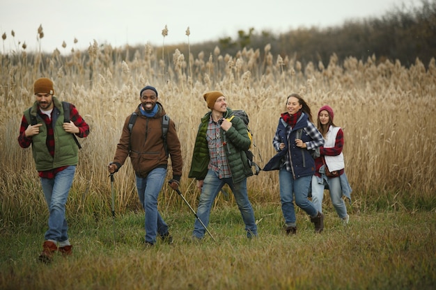 Foto groep vrienden op een kampeer- of wandeltocht in de herfstdag. mannen en vrouwen met toeristische rugzakken die door het bos gaan, pratend, lachend. vrijetijdsbesteding, vriendschap, weekend.