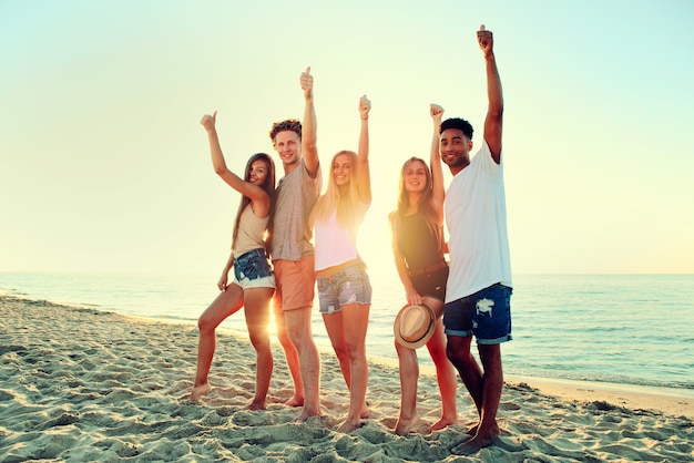 Groep vrienden op het strand met omhoog duimen