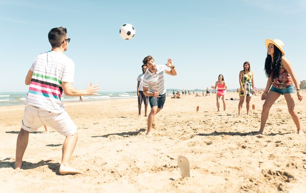 Groep vrienden plezier op het strand voetballen