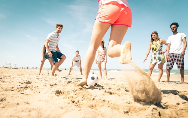 Groep vrienden voetballen op het strand