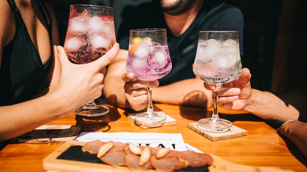 Groep vrienden zittend op het zomerterras met cocktails en snacks op tafel