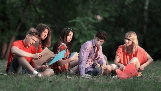 Groep vriendenstudenten die op het gras in het park zitten