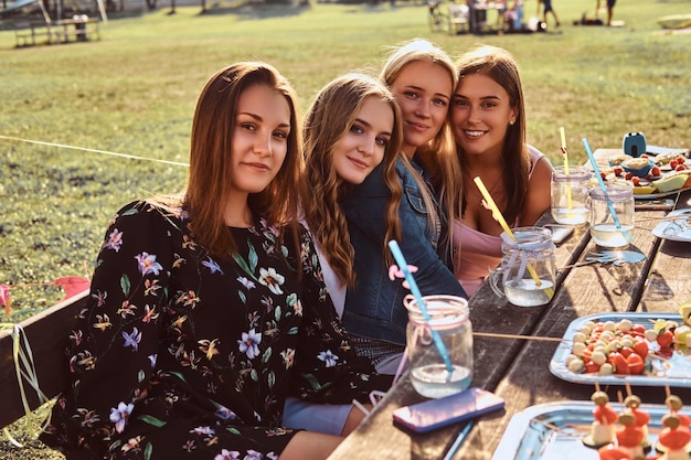 Groep vriendinnen die samen aan tafel zitten om een verjaardag te vieren in het buitenpark.