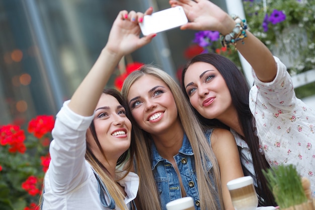 Foto groep vriendinnen maken van een selfie foto op de mobiele camera glimlachen. mooie vrouwen plezier in het café. jonge meisjes lachen