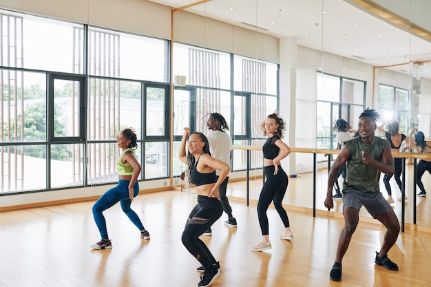 Groep vrolijke dansers oefenen nieuwe beweging tijdens het repeteren in de studio