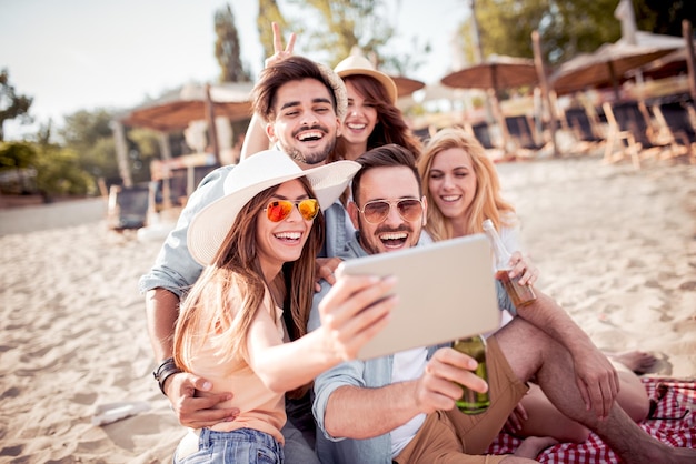 Groep vrolijke vrienden die samen selfie op het strand nemen