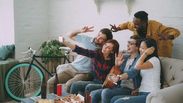 Groep vrolijke vrienden die selfie-foto's maken op de camera van de smartphone terwijl ze thuis vieren op een feestje met bier en snacks