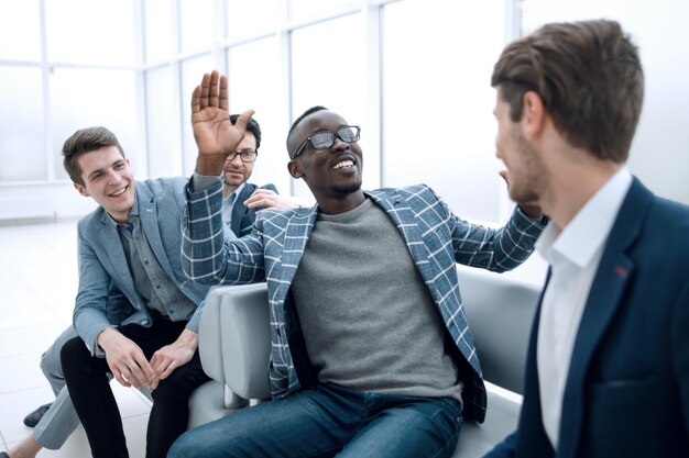 Groep vrolijke zakenmensen die in de lobby van het kantoor zitten