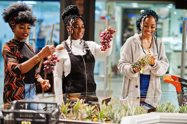 Groep vrouwen die met boodschappenwagentje exotische vruchten in de supermarkt van de kruidenierswinkelopslag kopen