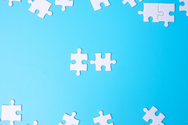 Groep witte puzzelstukjes op blauwe achtergrond. Concept van oplossingen, missie, succes, doelen, samenwerking, partnerschap, strategie en puzzeldag