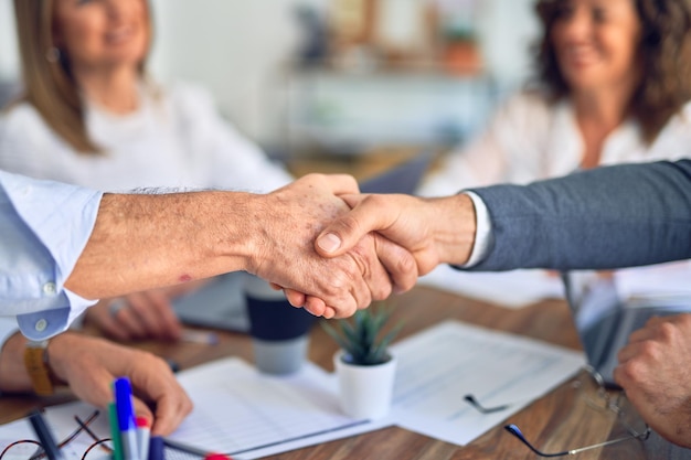 Groep zakelijke werknemers die gelukkig en zelfverzekerd glimlachen Samenwerken met een glimlach op het gezicht handen schudden op kantoor