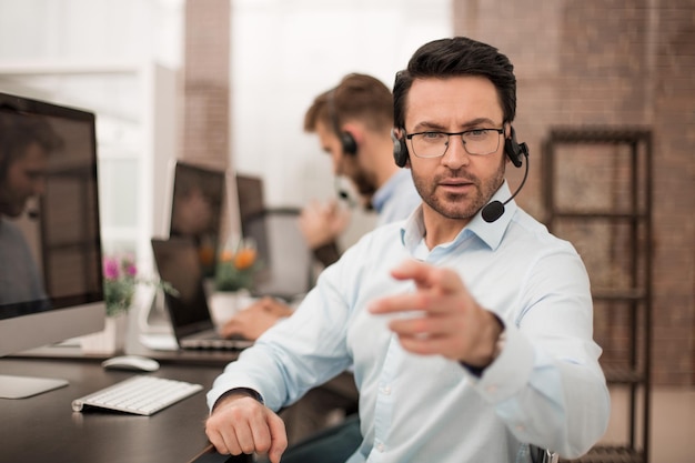 Groep zakencollega's met hoofdtelefoons die computers gebruiken bij bureaubusinessconcept