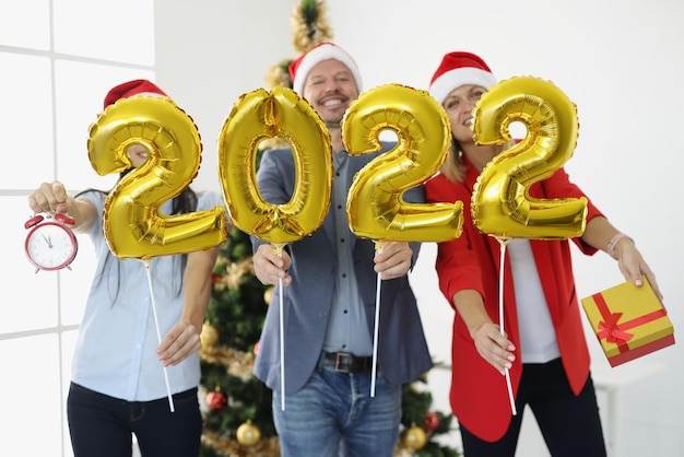 Groep zakenmensen die gouden heliumballonnen met nummers op de achtergrond van kerstmis houden