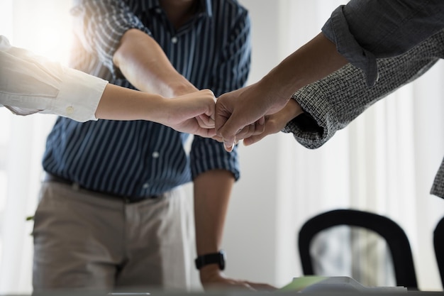 Groep zakenmensen die hun handen in elkaar steken om samen te werken op een houten achtergrond in het concept van de groepsondersteuning voor teamwerkovereenkomsten